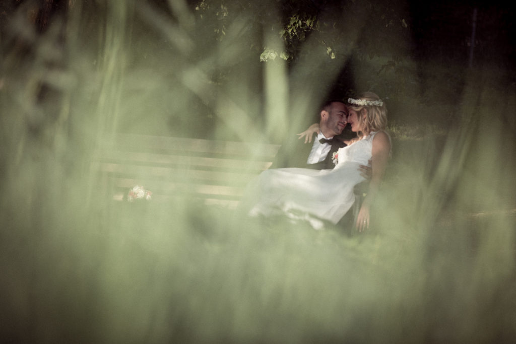 Hochzeitsfotograf_freiburg_basel_zuerich_portraitshooting_sonnenaufgang_paar_kuesst_auf_der_bank_seepark